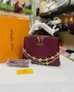 Burgundy structured top-handle bag with floral chains and matching strap