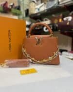 Tan structured top-handle bag with floral chains and matching strap